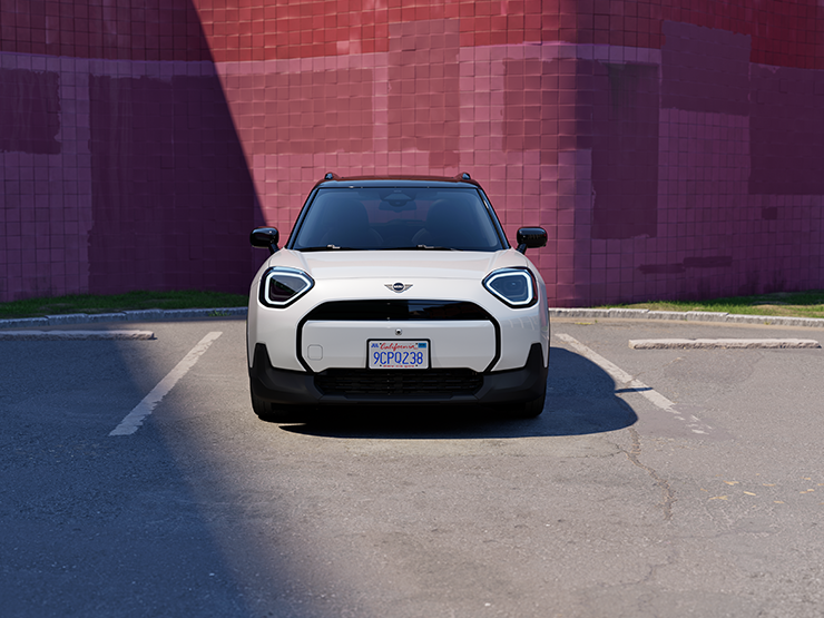 Parkinge stovinčio baltos Nanuq White spalvos visiškai elektrinio  MINI Aceman vaizdas iš priekio su juodos spalvos stogu.
