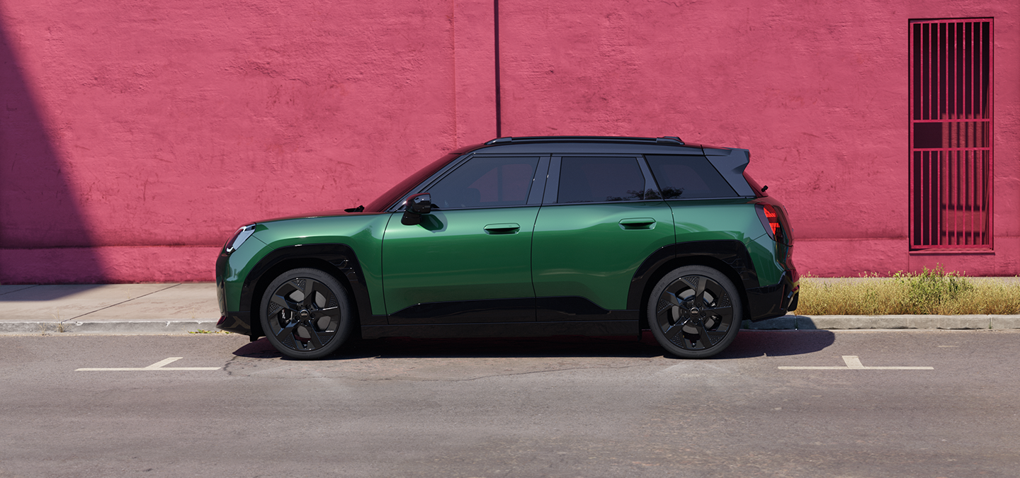Žalios British Racing Green spalvos visiškai elektrinio MINI Aceman vaizdas iš šono su juodos spalvos stogu