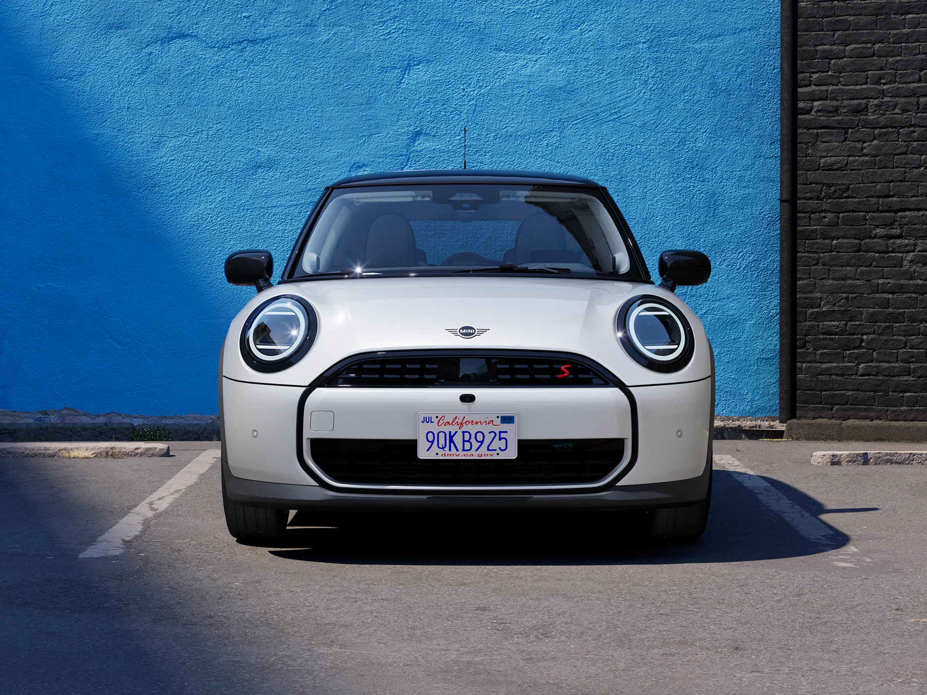 Parkinge stovinčio baltos Nanuq White spalvos MINI Cooper vaizdas iš priekio su juodu stogu.