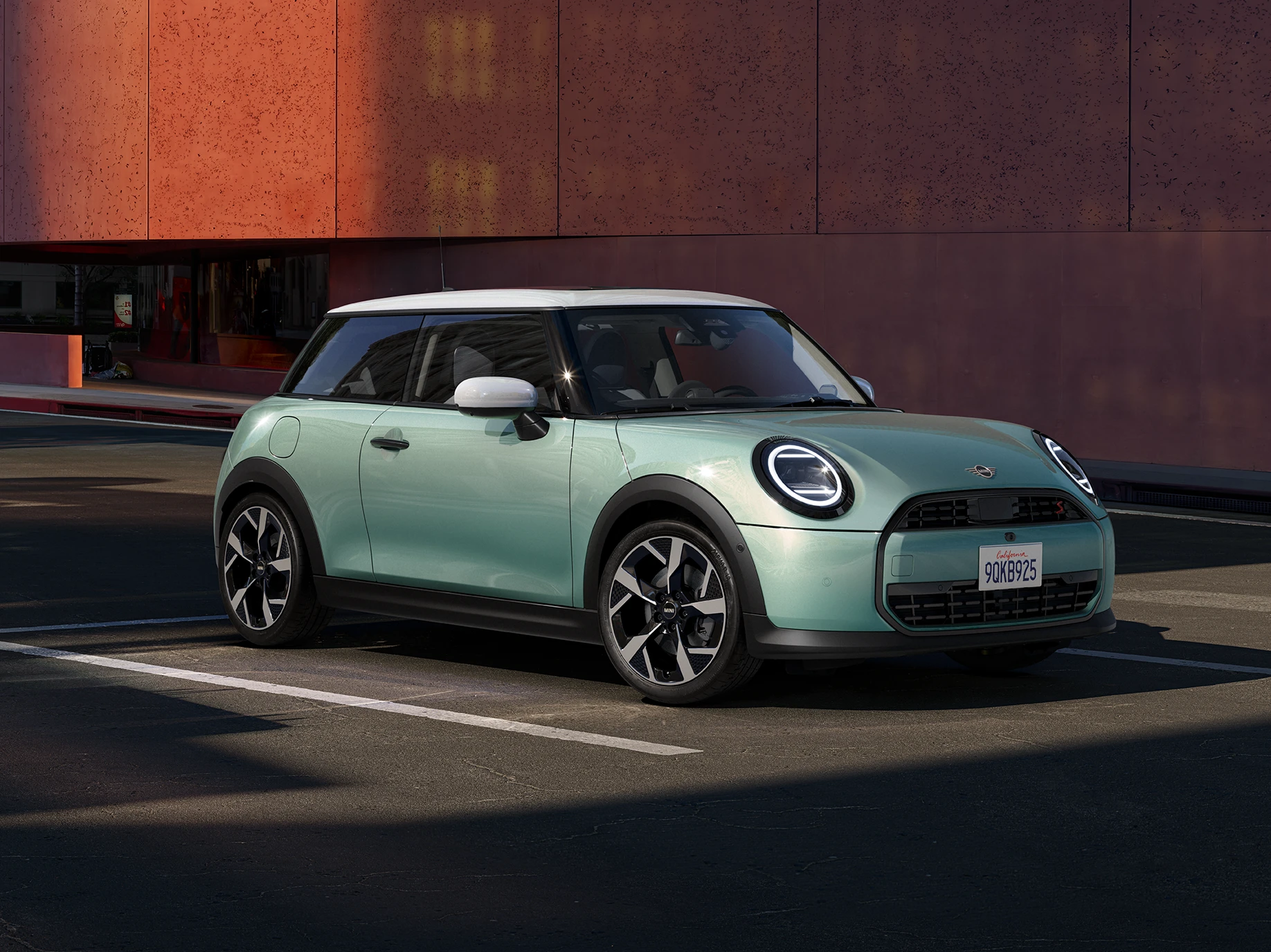 Žalios Ocean Wave Green spalvos MINI Cooper vaizdas iš priekinio šono su baltu stogu.