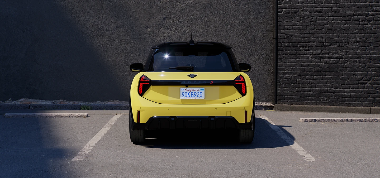 Parkinge stovinčio geltonos Sunnyside Yellow spalvos MINI Cooper vaizdas iš galo su juodu stogu.