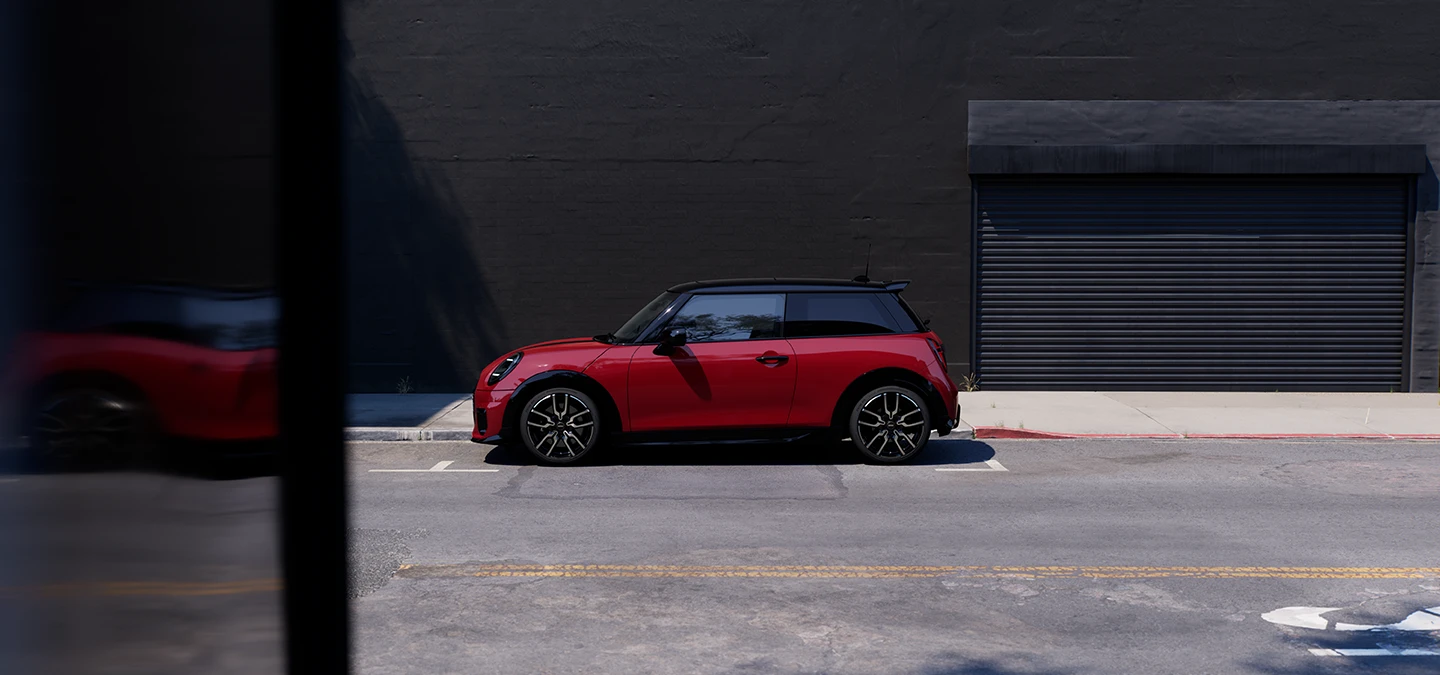 Parkinge stovinčio raudonos Chili Red spalvos MINI Cooper vaizdas iš šono su juodu stogu.
