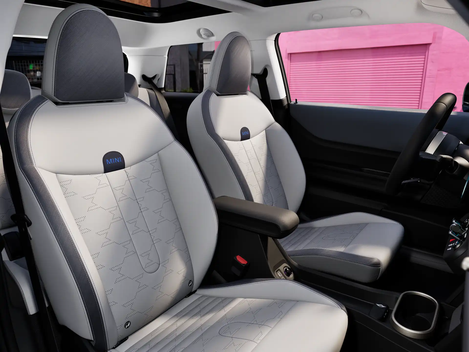 MINI Cooper interjeras su prietaisų skydeliu, vairu, apvaliu ekranu, panoraminiu stikliniu stoglangiu ir priekinių sėdynių atlošais.