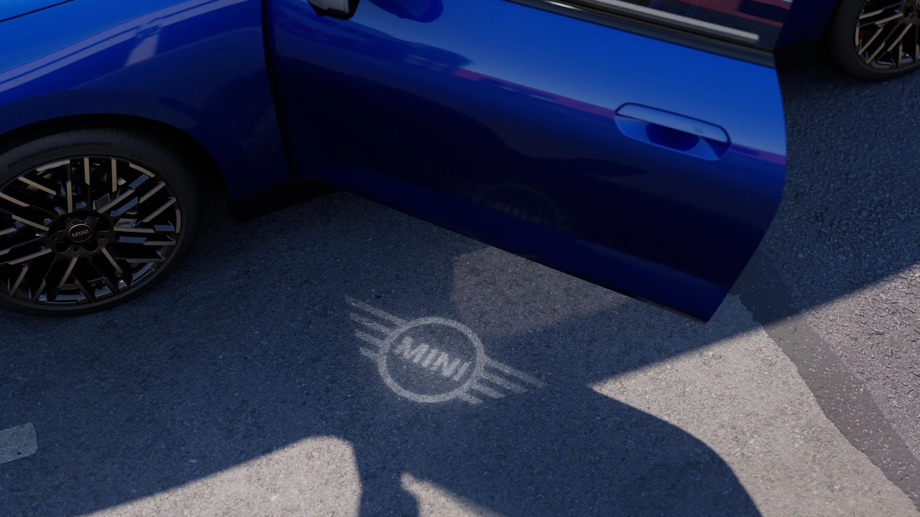 Visiškai elektrinio MINI Cooper eksterjero vaizdas su atviromis durimis ir MINI logotipu durelių projekcijoje ant grindinio