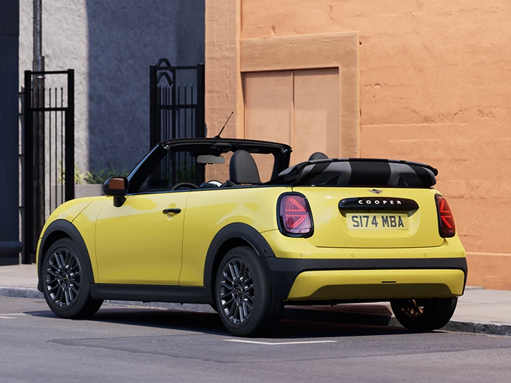 Parkinge stovinčio MINI Cooper kabrioleto  geltonos Sunnyside Yellow spalvos galinis vaizdas iš kairės.