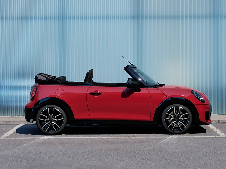 Gatvėje stovinčio raudonos Chili Red spalvos MINI Cooper kabrioleto vaizdas iš šono
