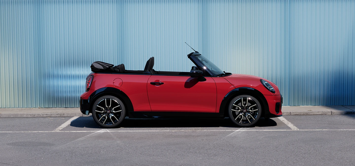 Gatvėje stovinčio raudonos Chili Red spalvos MINI Cooper kabrioleto vaizdas iš šono