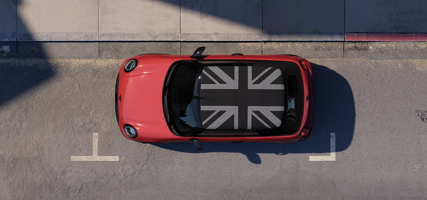 Gatvėje stovinčio pilkos Copper Grey spalvos MINI Cooper kabrioleto su MINI Yours stogu vaizdas iš viršaus