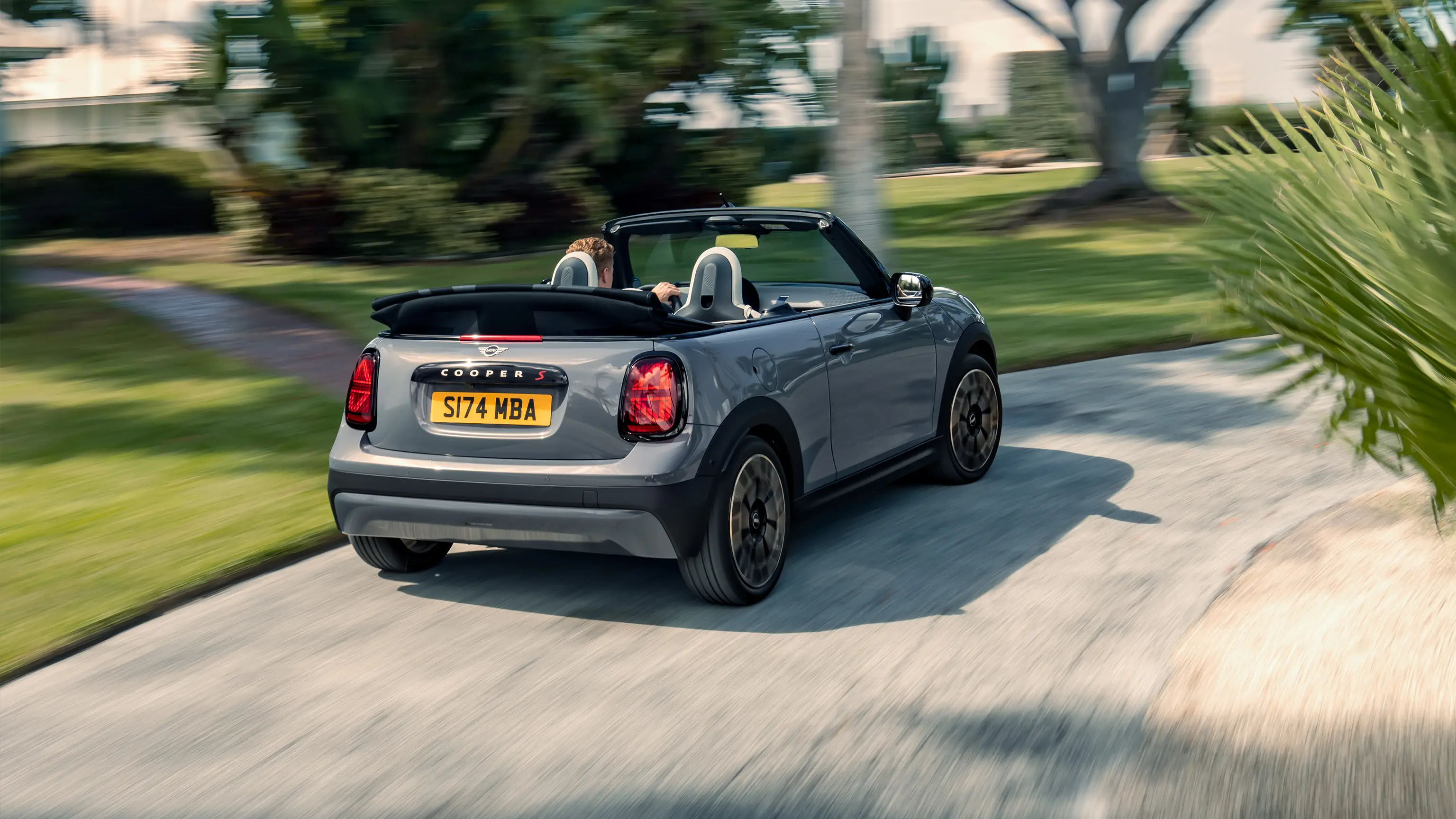 Važiuojančio pilkos Copper Grey spalvos MINI Cooper kabrioleto vaizdas iš galo 