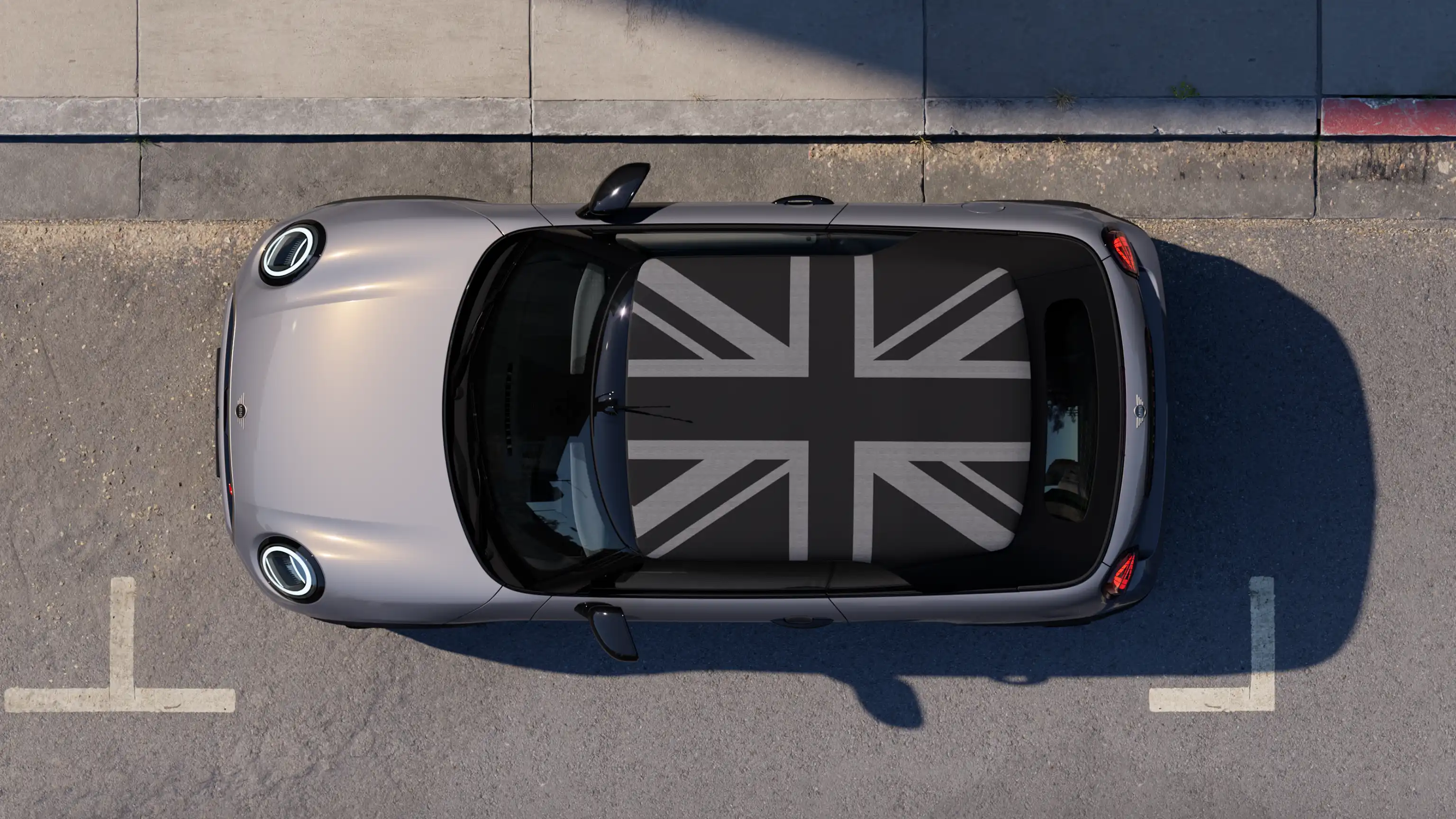 Gatvėje stovinčio pilkos Copper Grey spalvos MINI Cooper kabrioleto su MINI Yours stogu vaizdas iš viršaus 