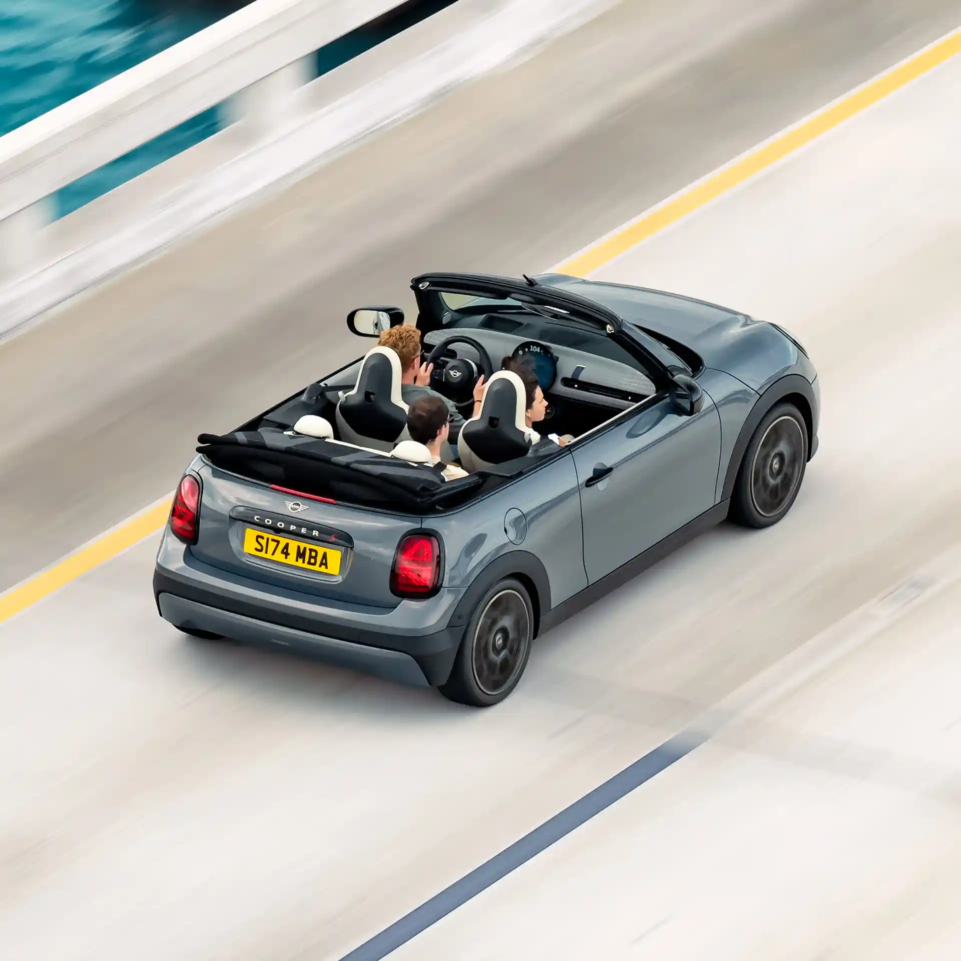Gatve važiuojančio MINI Cooper kabrioleto galinis vaizdas iš viršaus