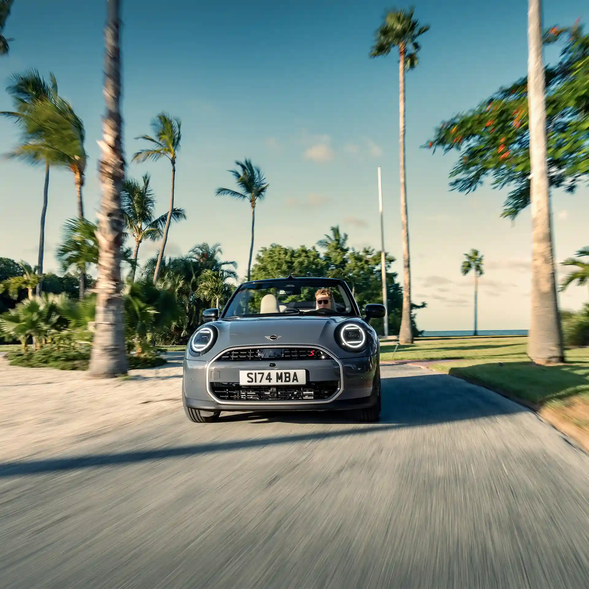 Gatve važiuojančio pilkos Copper Grey spalvos MINI Cooper kabrioleto vaizdas iš priekio