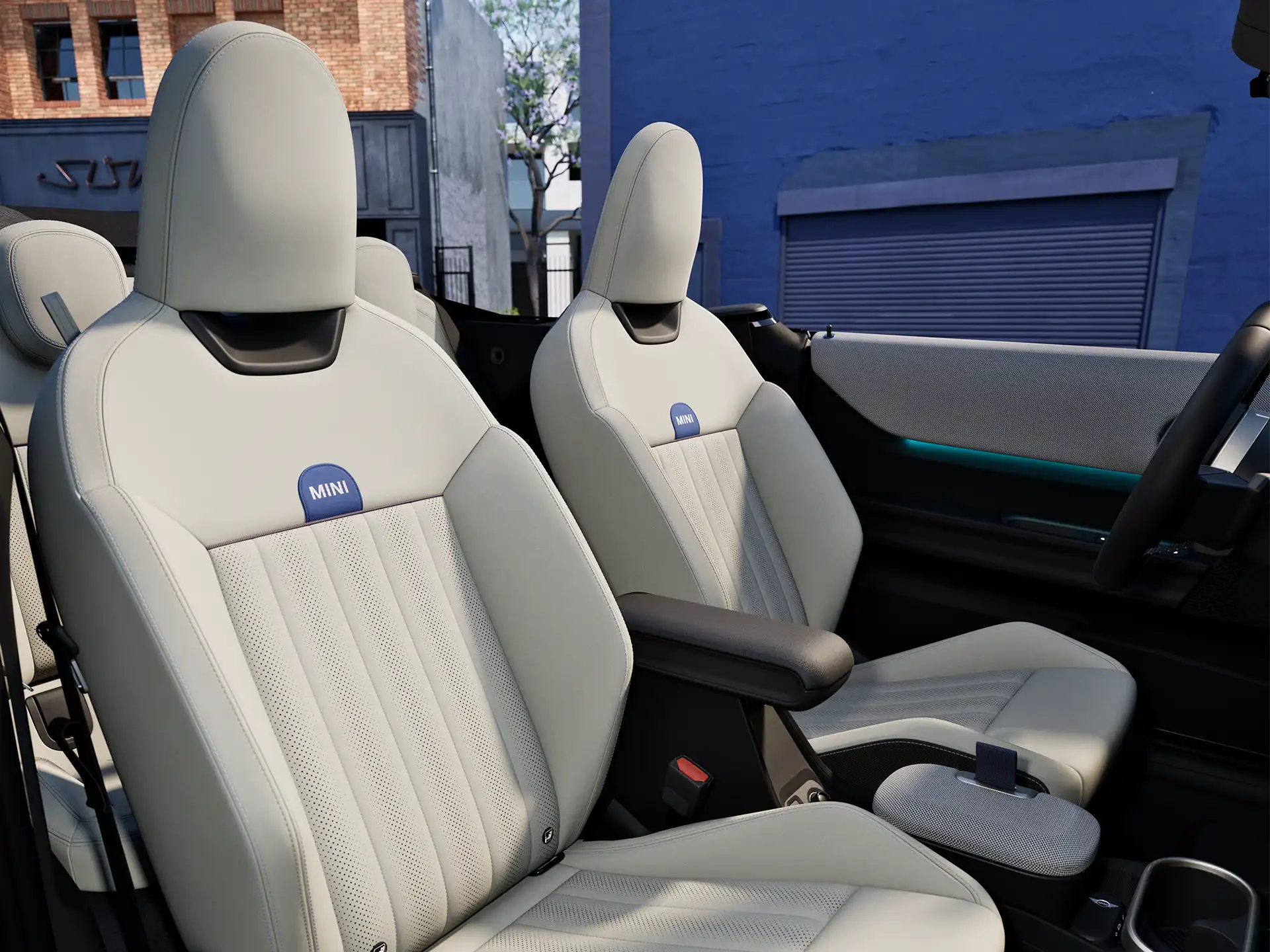 MINI Cooper kabrioleto interjero vaizdas su prietaisų skydeliu, vairu, apvaliu ekranu ir priekinių sėdynių atlošais.