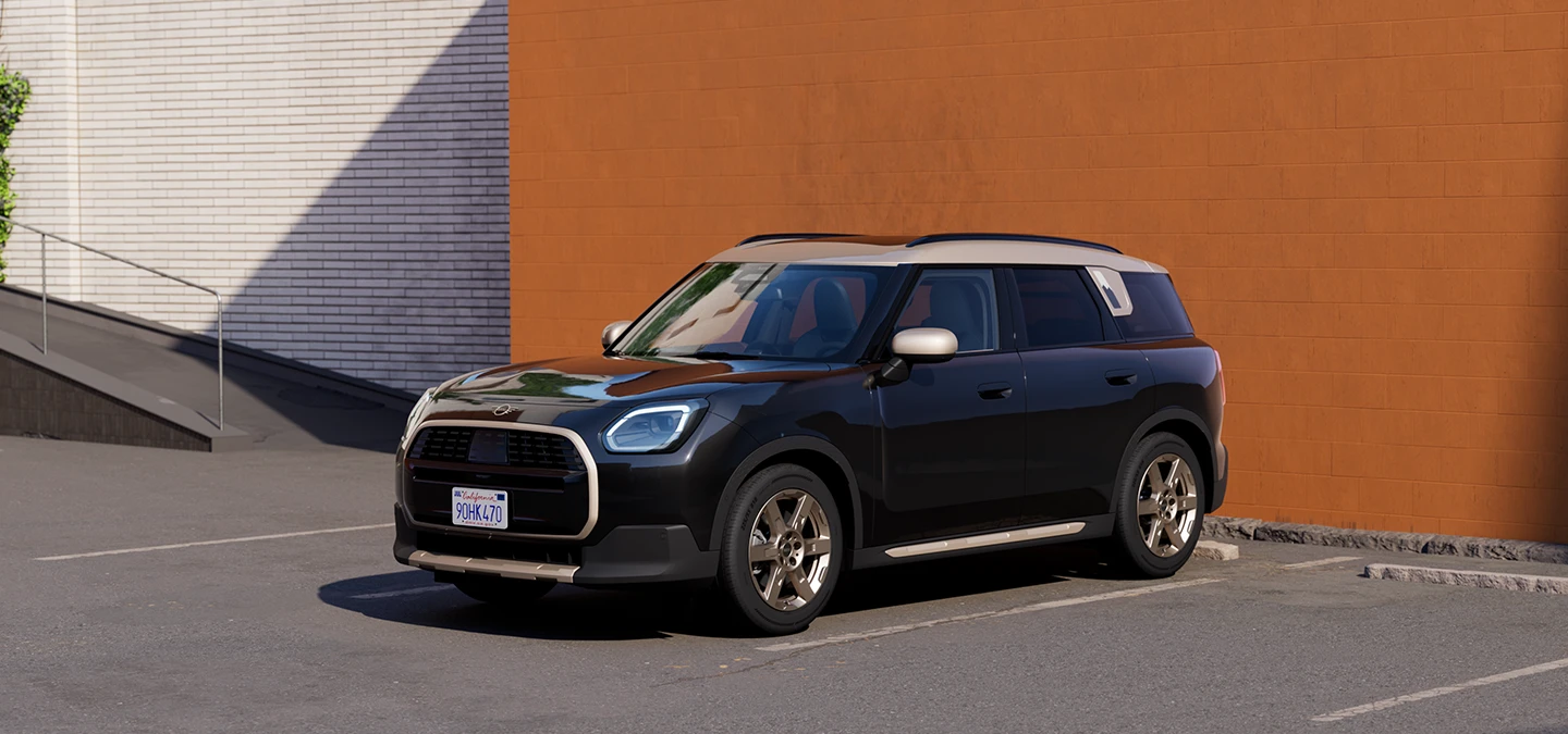 Parkinge stovinčio MINI Countryman juodos Midnight Black spalvos su pilkos Vibrant Silver spalvos stogu šoninis vaizdas iš priekio.