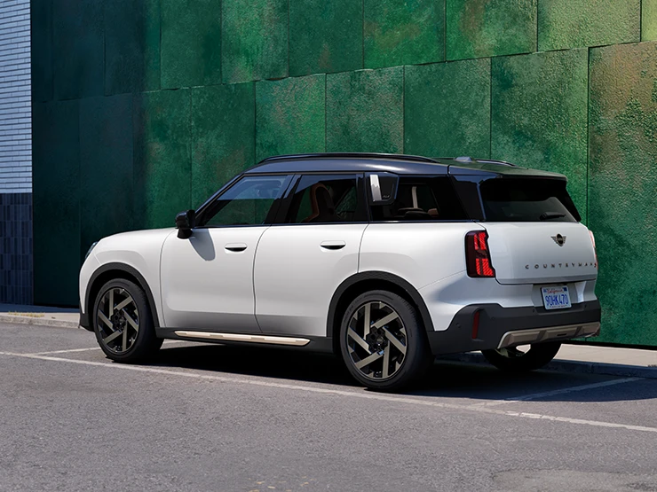 Gatvėje stovintis MINI Countryman baltos Nanuq White spalvos su juoda stogo bagažine.