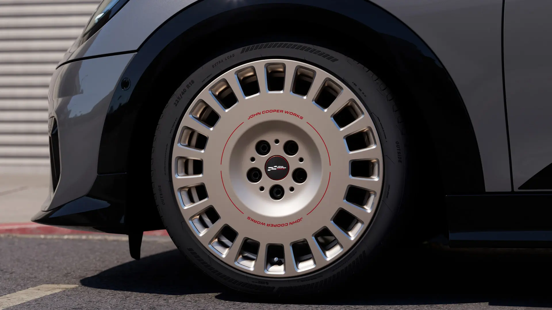 MINI JCW 18 colių Rallye Spoke 964 deimantinio šlifavimo ratlankiai pilkos Frozen Midnight Grey spalvos su žvaigždute paženklintomis ir MINI patvirtintomis padangomis.