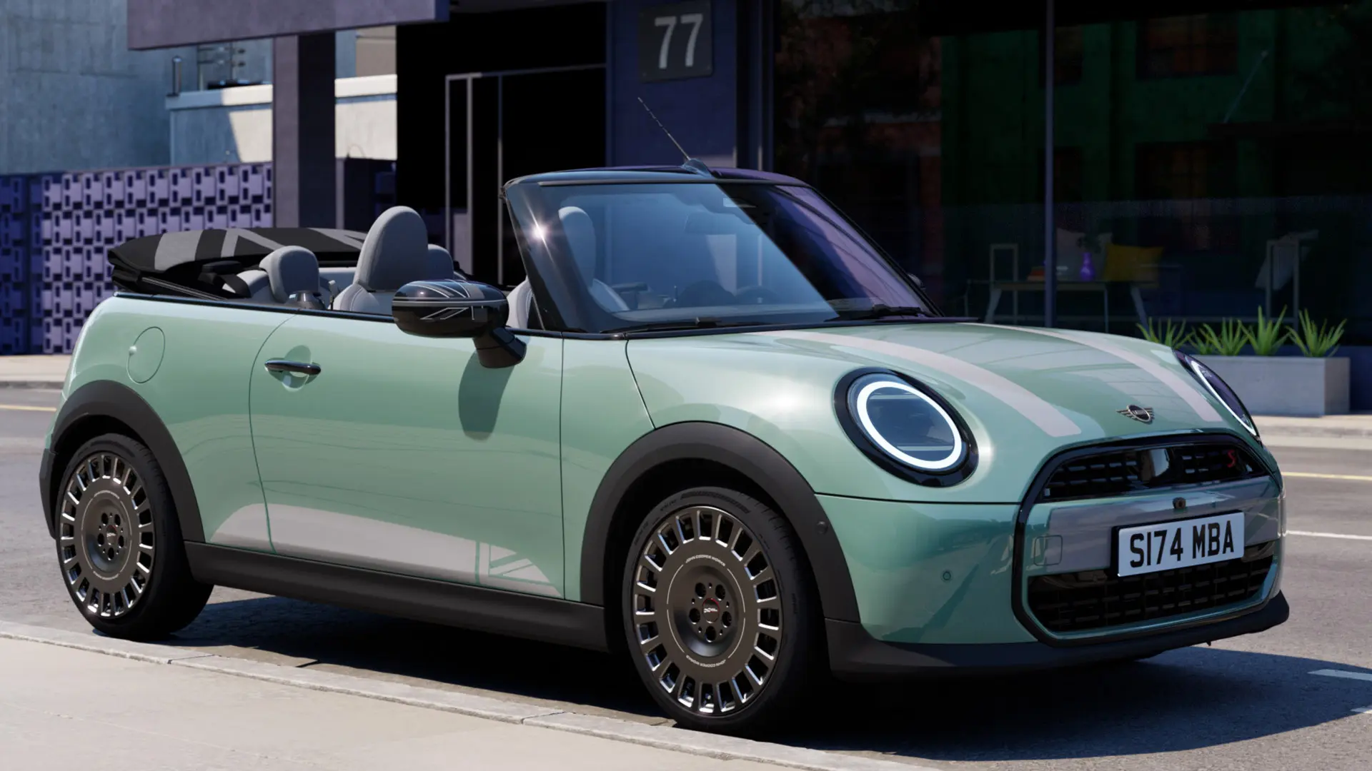 Žalios Ocean Wave Green spalvos MINI kabrioletas su MINI Heritage baltais lipdukais ant variklio gaubto.