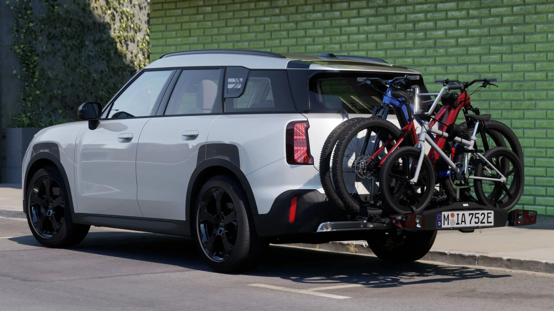 MINI Aceman baltos Nanuq White spalvos su MINI gale tvirtinamu dviračių laikikliu Pro 3.0, ant kurio transportuojami du kalnų dviračiai ir vaikiškas dviratis.