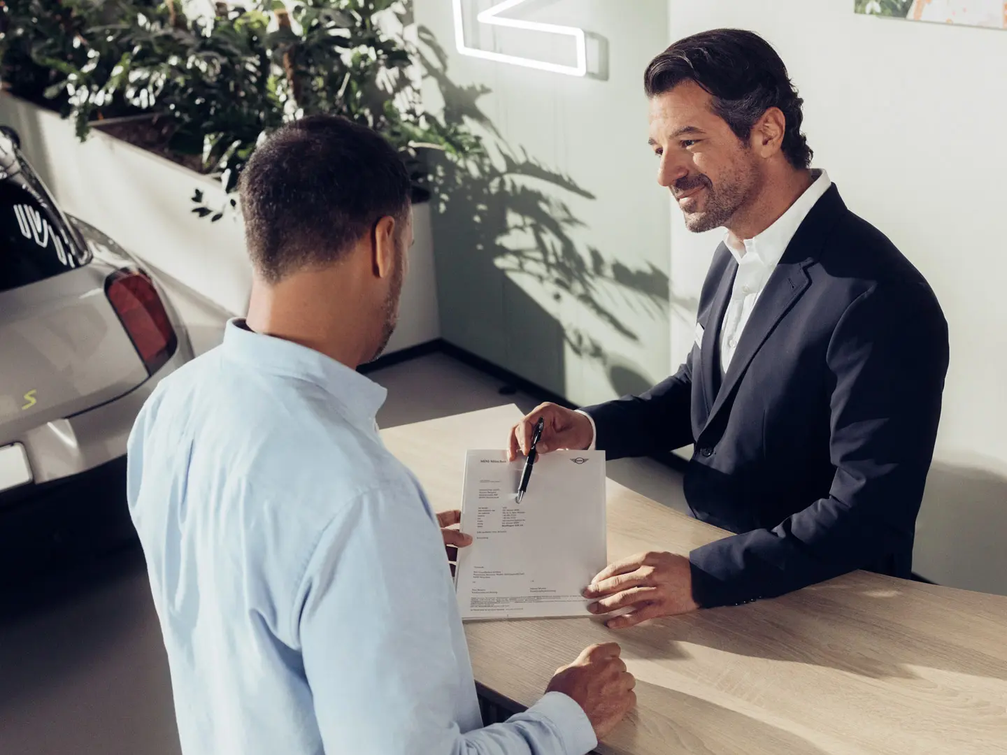 MINI serviso darbuotojas konsultuoja klientą apie MINI padangų draudimo galimybes.