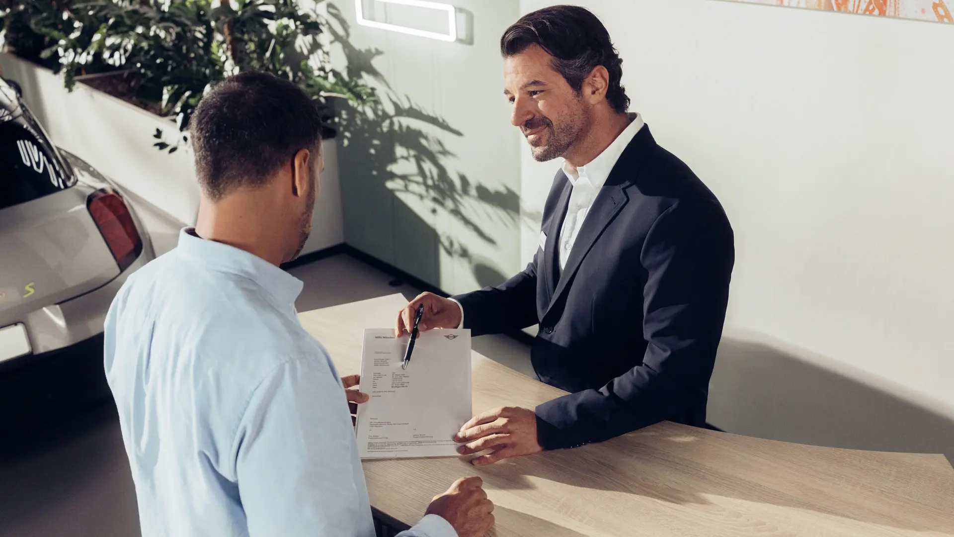 MINI serviso darbuotojas konsultuoja klientą apie MINI padangų draudimo galimybes.