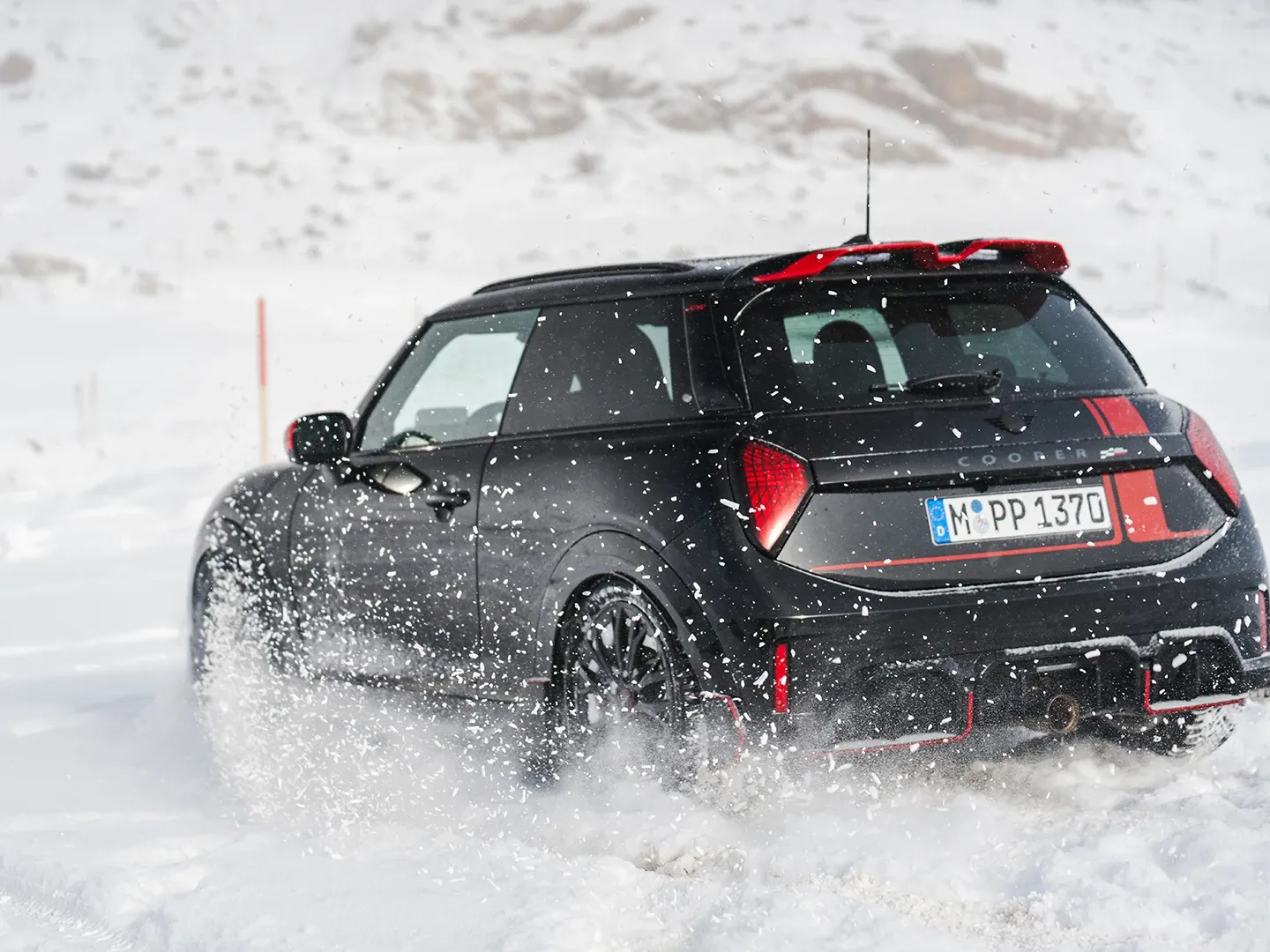 MINI Cooper JCW galinis vaizdas važiuojant per sniegą.