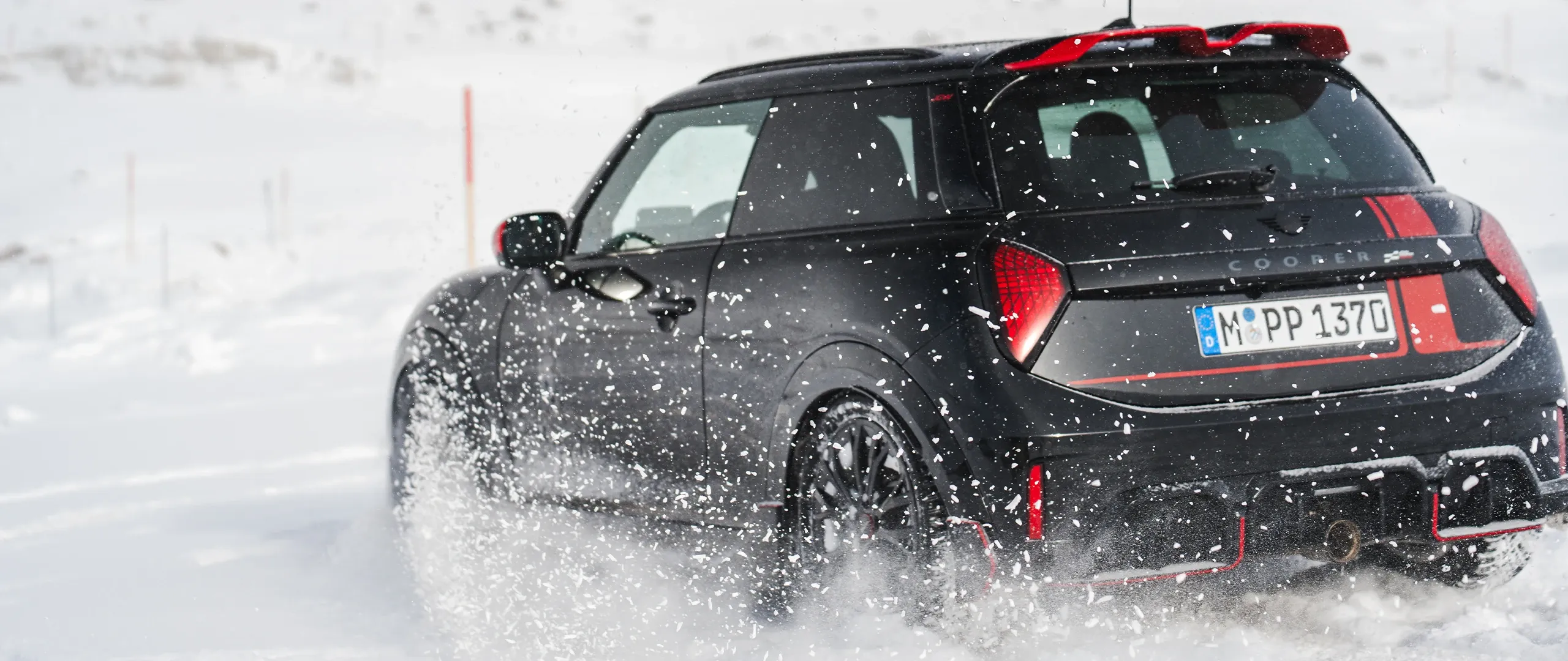 MINI Cooper JCW galinis vaizdas važiuojant per sniegą.
