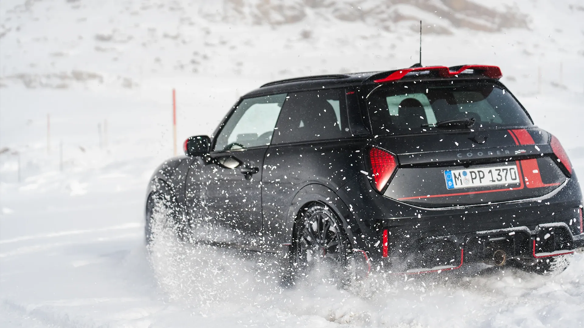 MINI Cooper JCW galinis vaizdas važiuojant per sniegą.