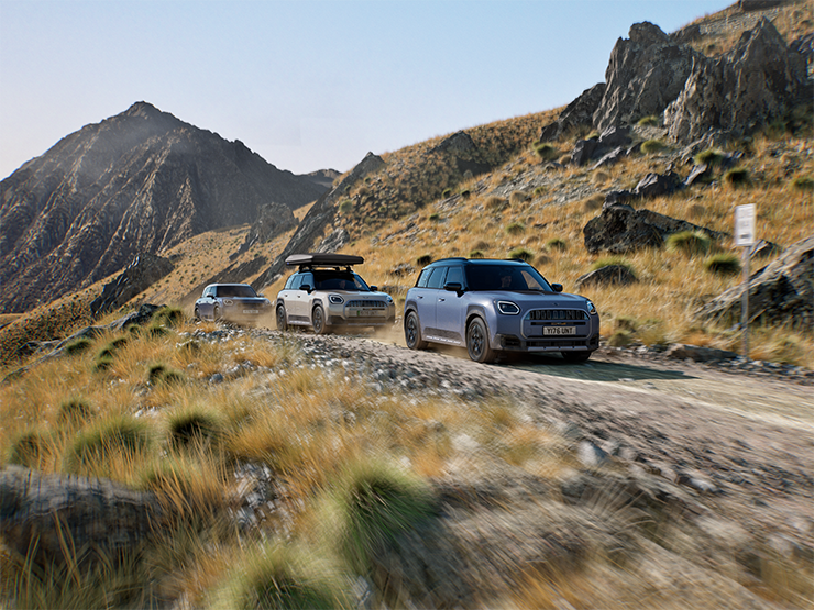 Kalnų keliu važiuojančių MINI Countryman Untamed Edition modelių vaizdas.