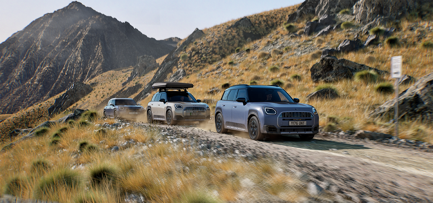 Kalnų keliu važiuojančių MINI Countryman Untamed Edition modelių vaizdas.