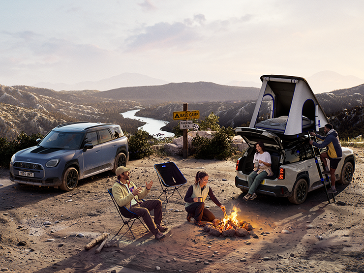 Dviejų MINI Countryman Untamed Edition automobilių vaizdas kalnuose saulei leidžiantis.